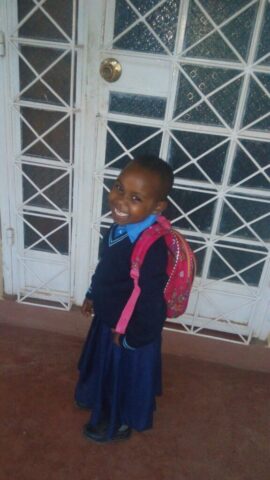 Ein strahlendes Gesicht mit neuer Schulkleidung zur neuen Schule